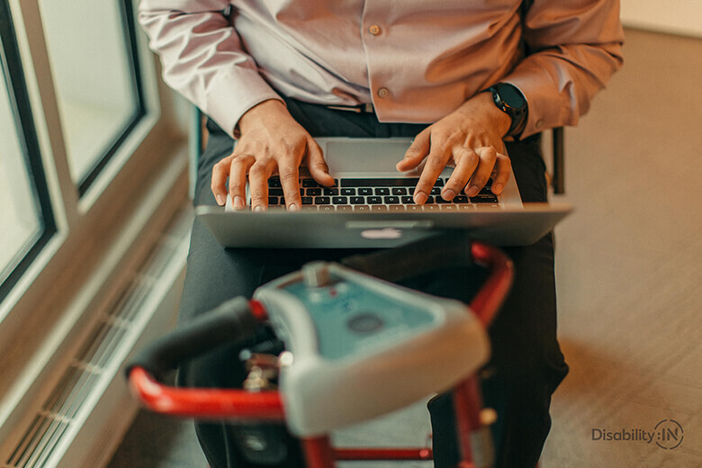 Man working on latop on a mobility scooter.