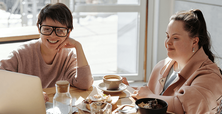 Two women smiling and looking at a laptop.